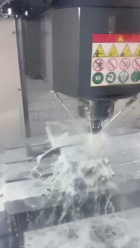 CNC machining center cutting a metal component under coolant